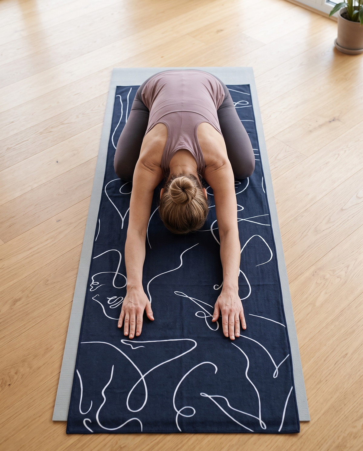 Frau in der Kindhaltung auf einem Yoga-Handtuch, das die Matte ganz abdeckt
