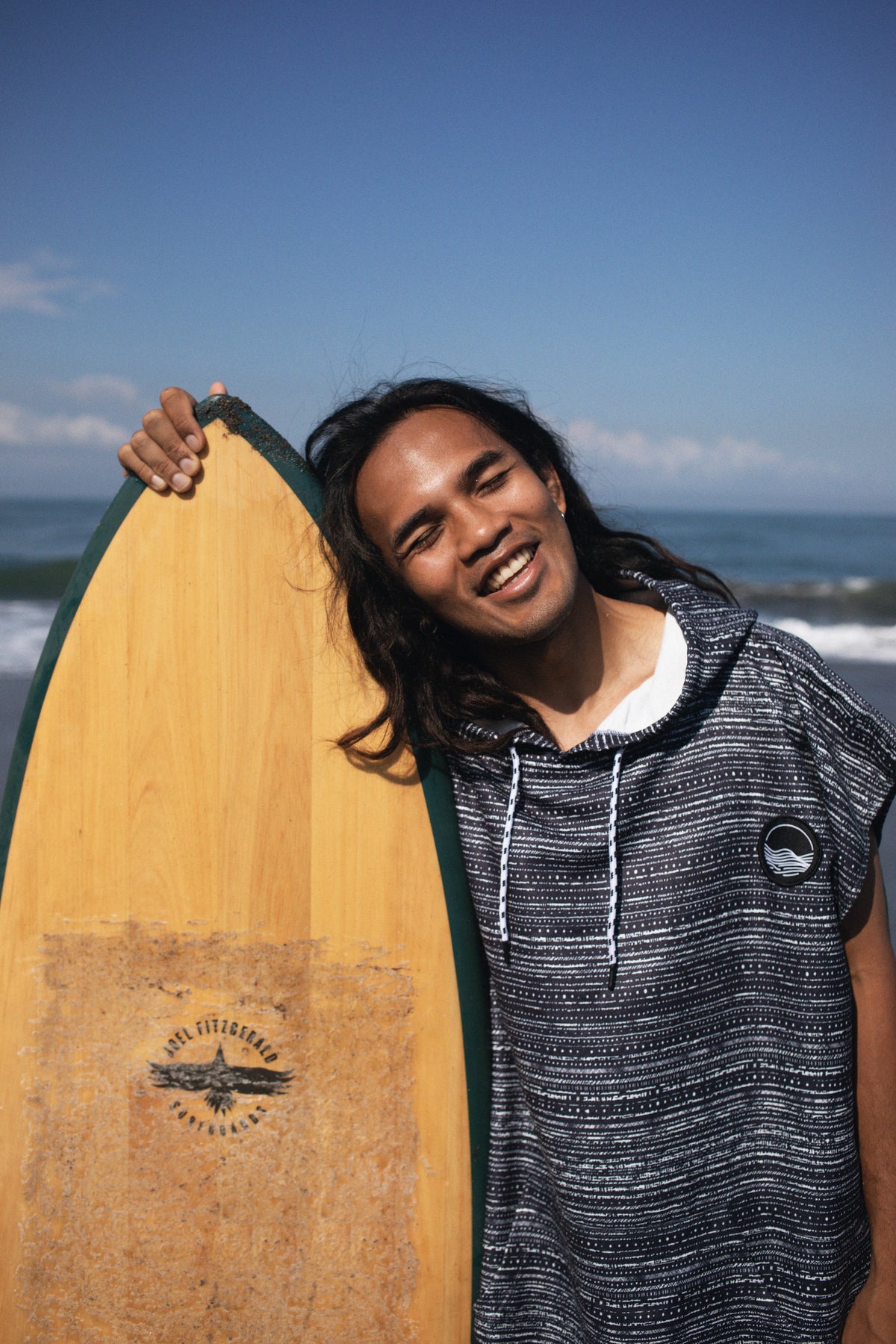 Surf-Poncho von Woods & Waves mit Surfboard am Strand